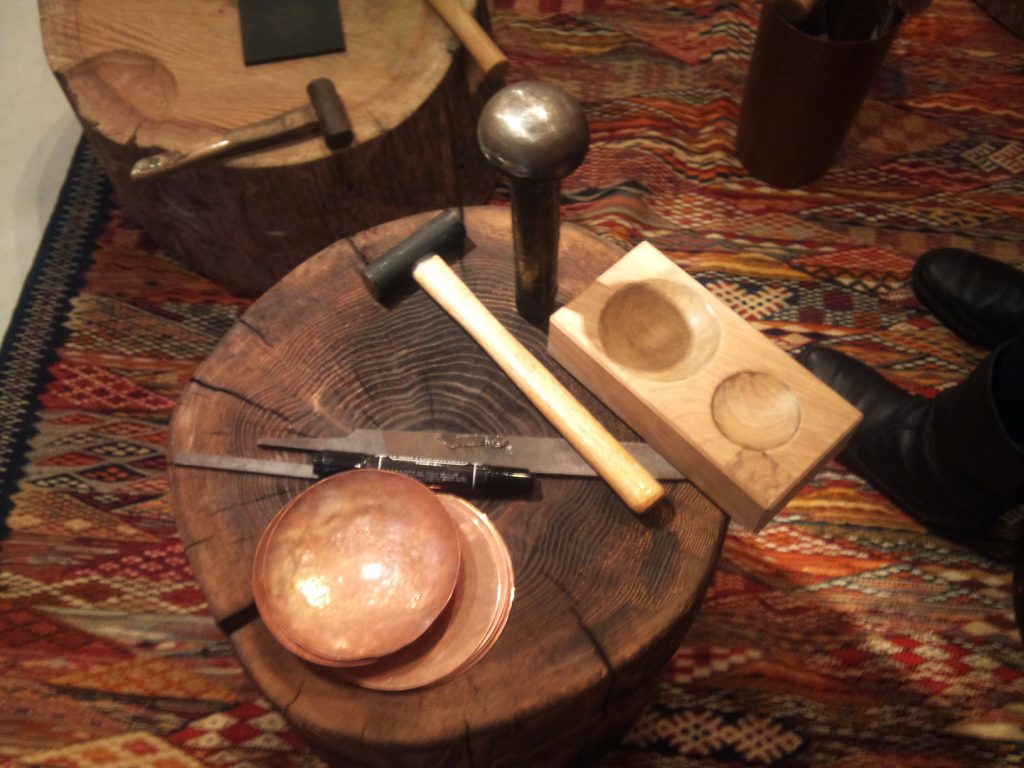 初心者らしく小皿の制作。 丸い銅板を、木や鉄の型に当て、金鎚で叩いて丸みをつけていきます。