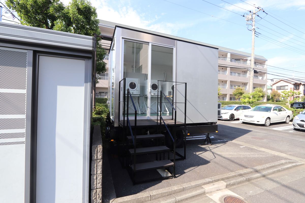 駐車場の脇に設置した白いトレーラーハウスと階段