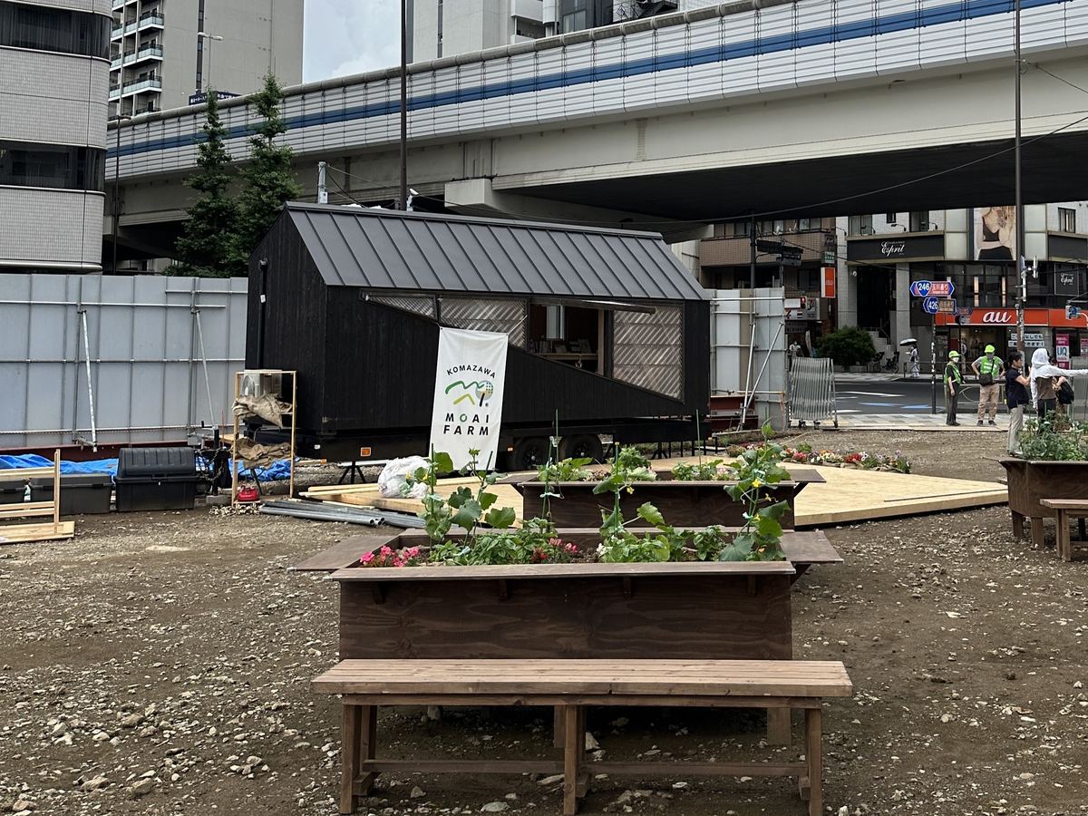 「KOMAZAWA MOAI FARM」の高架下に置かれた、黒い外壁の事務所トレーラー「HAWK」