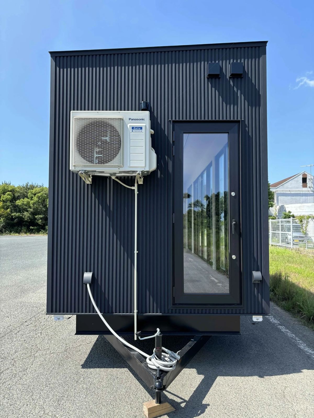 中古の9m大開口トレーラーハウスを後ろから見たところ（エアコンの室外機と車輪）