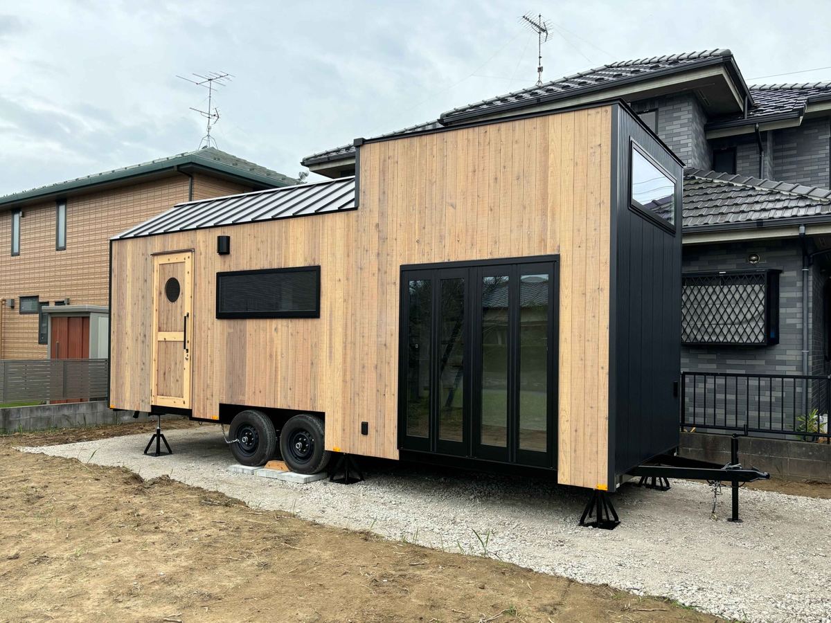住宅の庭に別棟として置かれた木の外壁のタイニーハウス