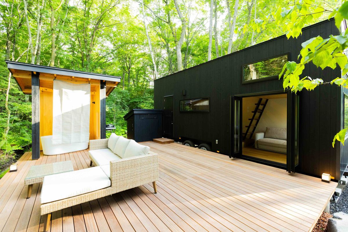 露天風呂の小屋とソファを置いた、森に面した広いウッドデッキ