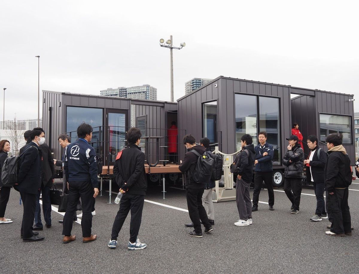 旅客ターミナルのトレーラーハウスの前に集まった見学者