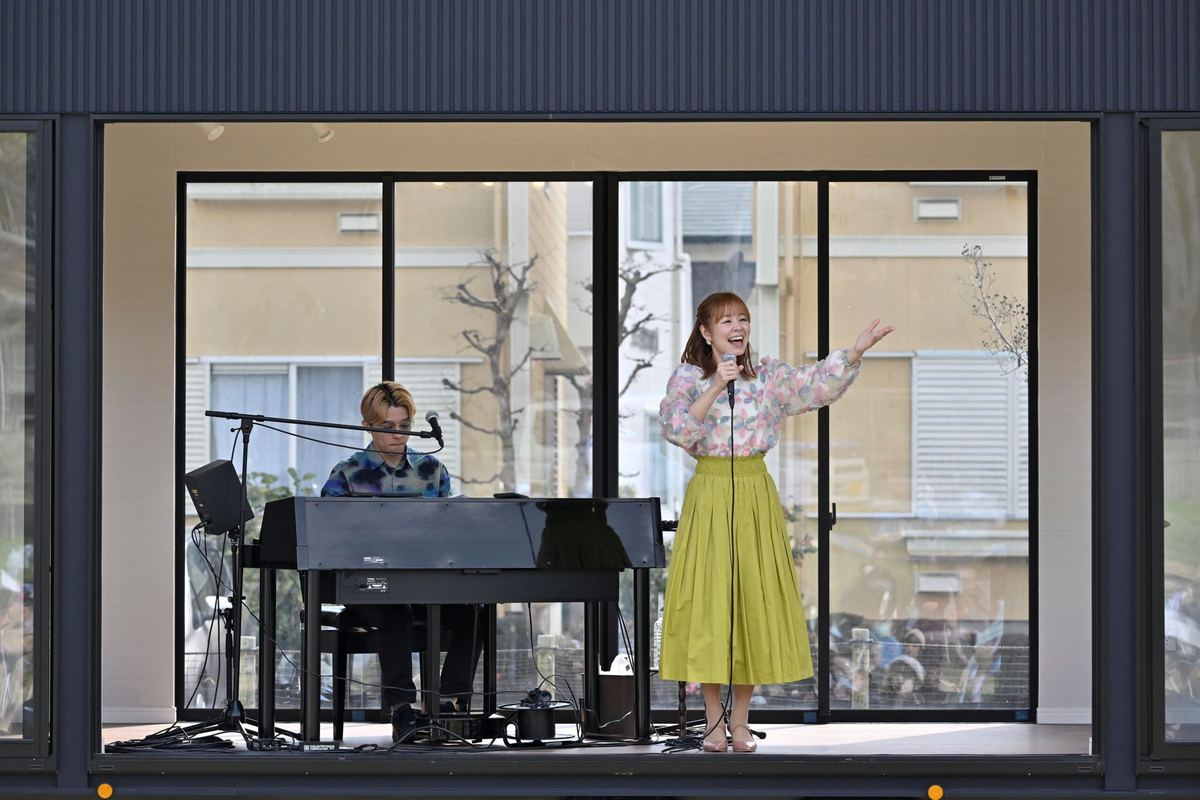トレーラーハウスのステージで、ピアノの伴奏に合わせて歌う出演者