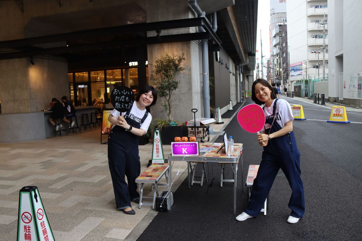 高架下で看板を持つ二人の女性