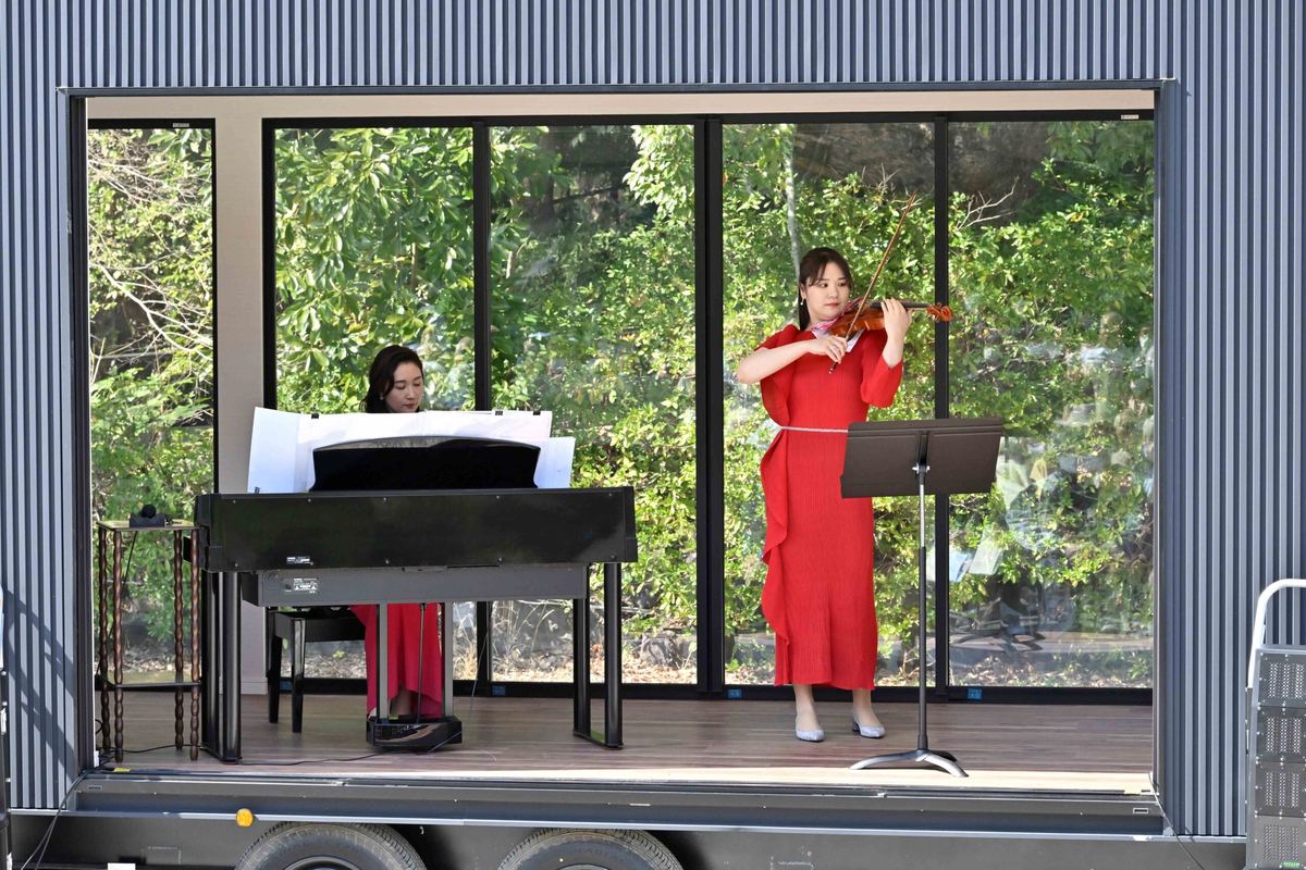 トレーラーハウスのステージで演奏する、ピアノとバイオリンの奏者