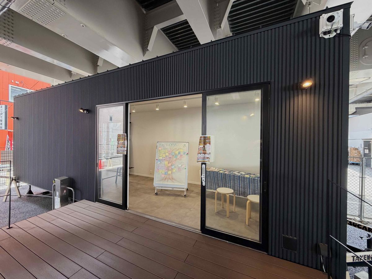 ガラス戸の黒い小屋とウッドデッキ