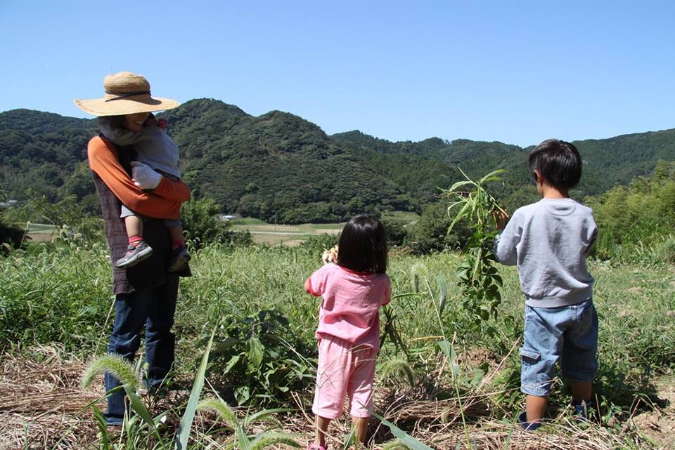 南房総の里山の前に佇む馬場さんと3人の子供たち