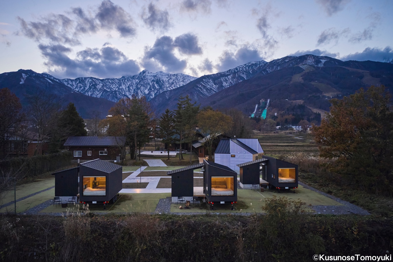 雪山を背に並ぶ、宿泊施設のトレーラーハウスの夕景