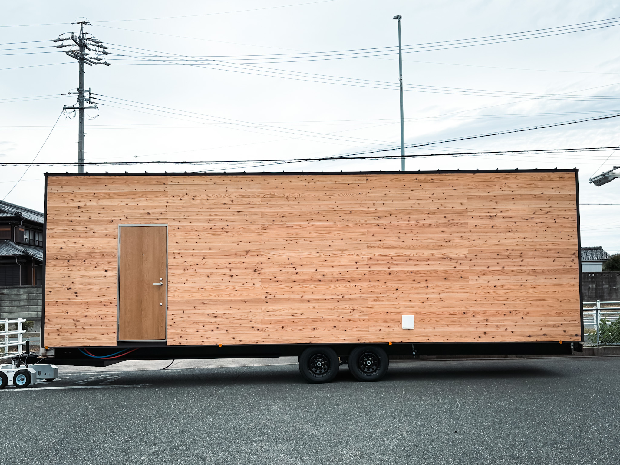 車輪の付いたシャーシに載った、木の外壁の大型トレーラーハウス